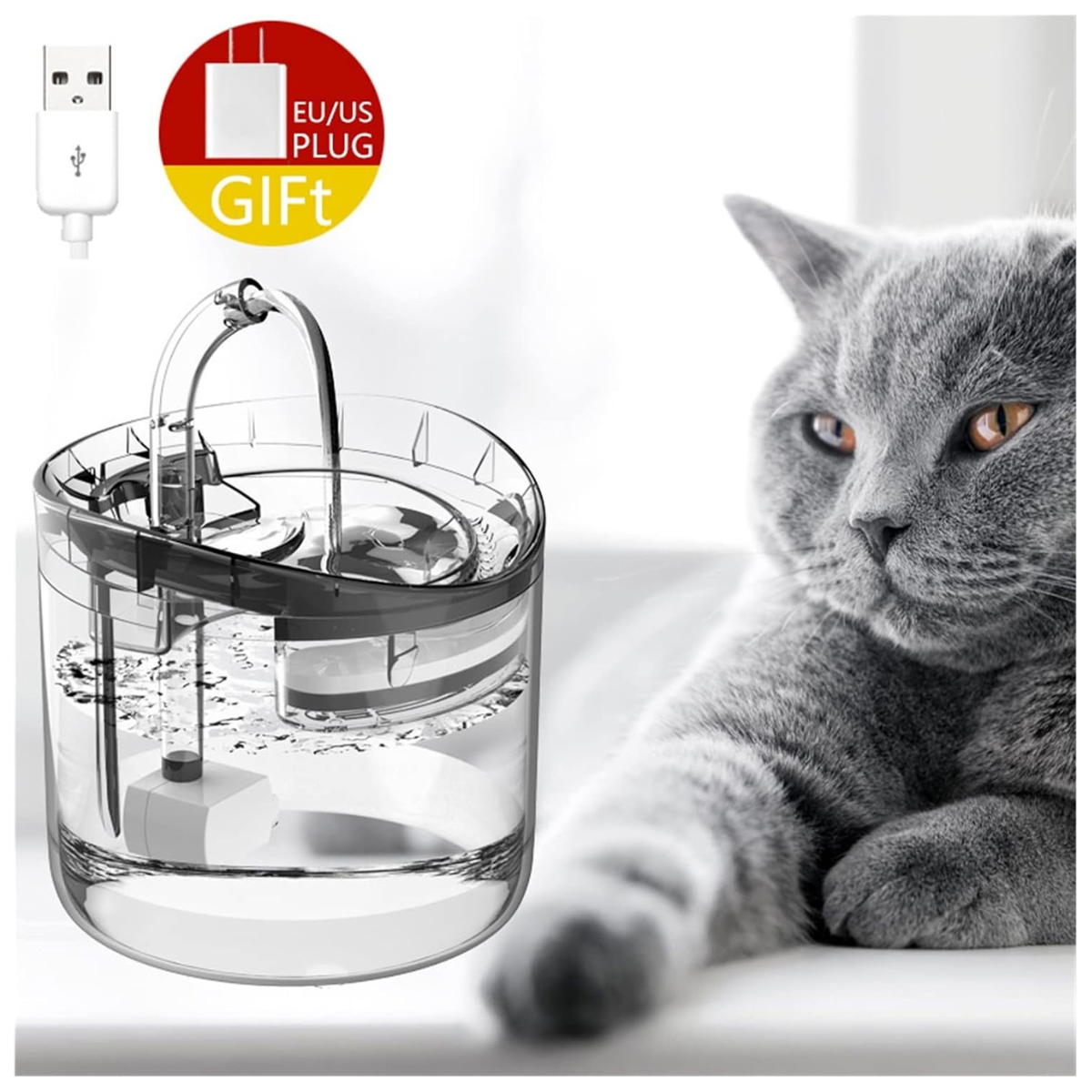 Fuente de agua transparente para mascotas con diseño elegante y compacto de 1.6 L, conectada mediante un cable USB. Incluye filtro de carbón activado para agua fresca y limpia. En la imagen, un gato gris observa la fuente en un entorno moderno